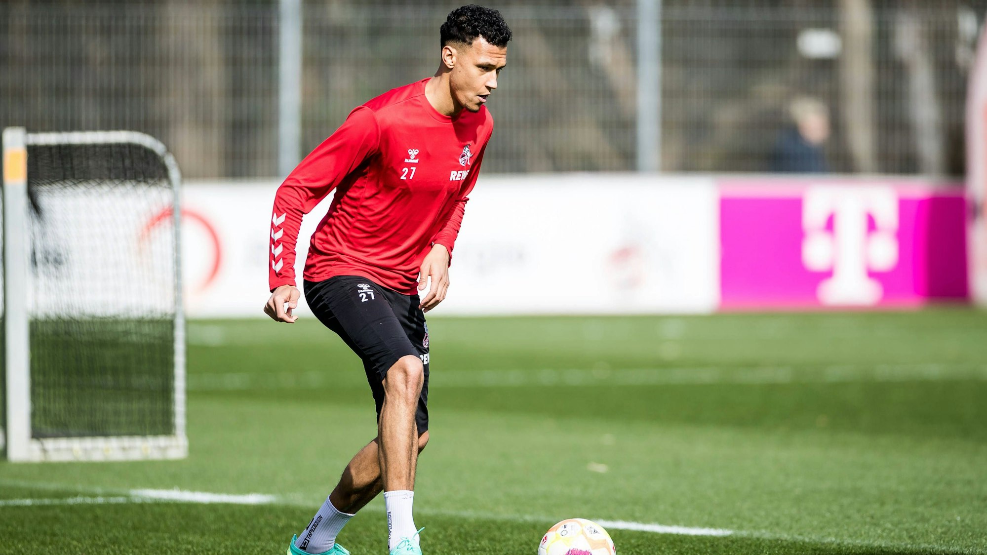 Davie Selke steht auf dem Fußballplatz und hat einen Ball vor sich liegen.