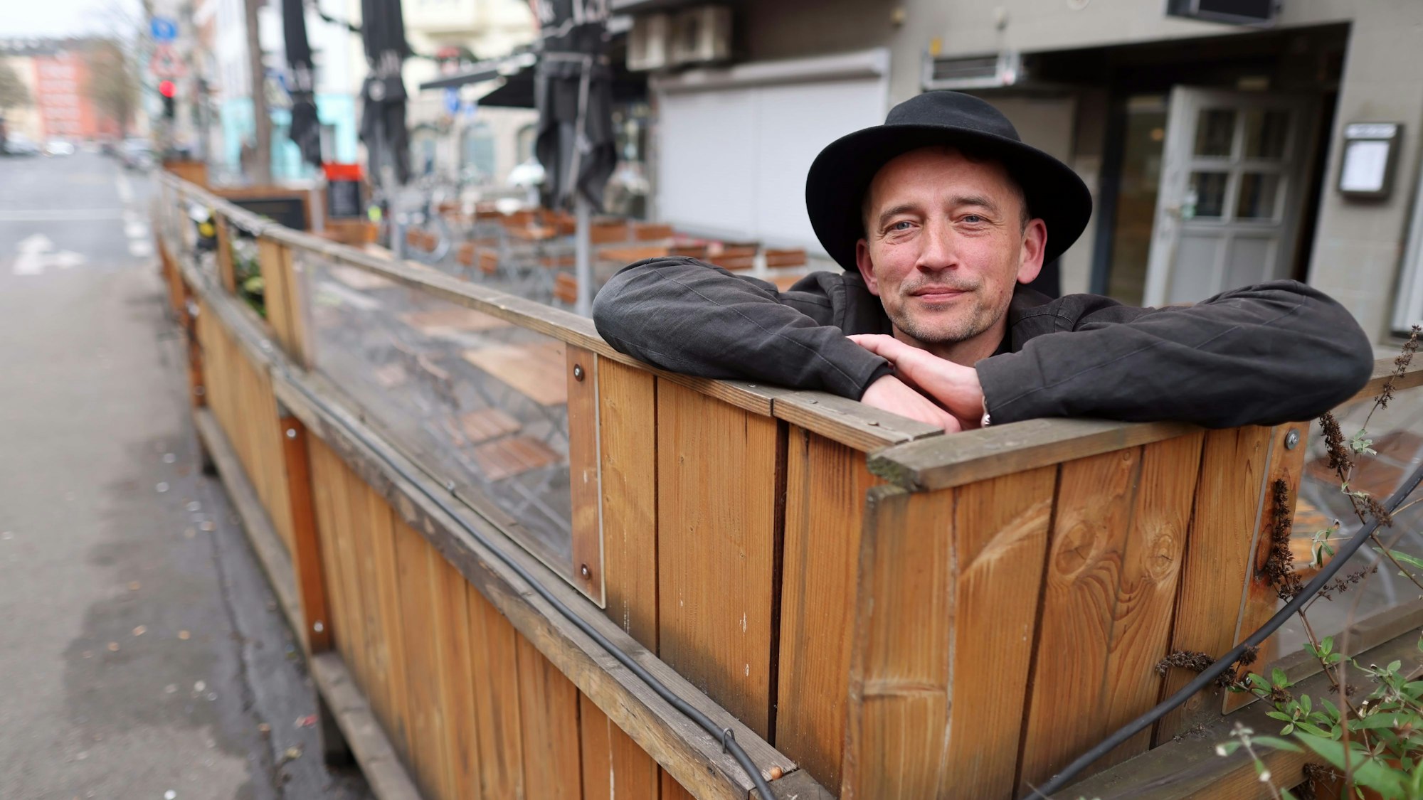 Ein Mann steht hinter einem Wetterschutz aus Holz.