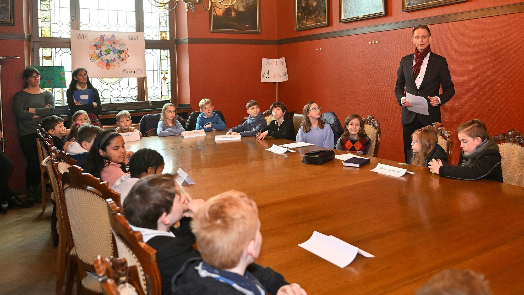 Grundschulkinder sitzen an einem Tisch im Rathaus und sprechen mit dem Beigeordneten Migenda.