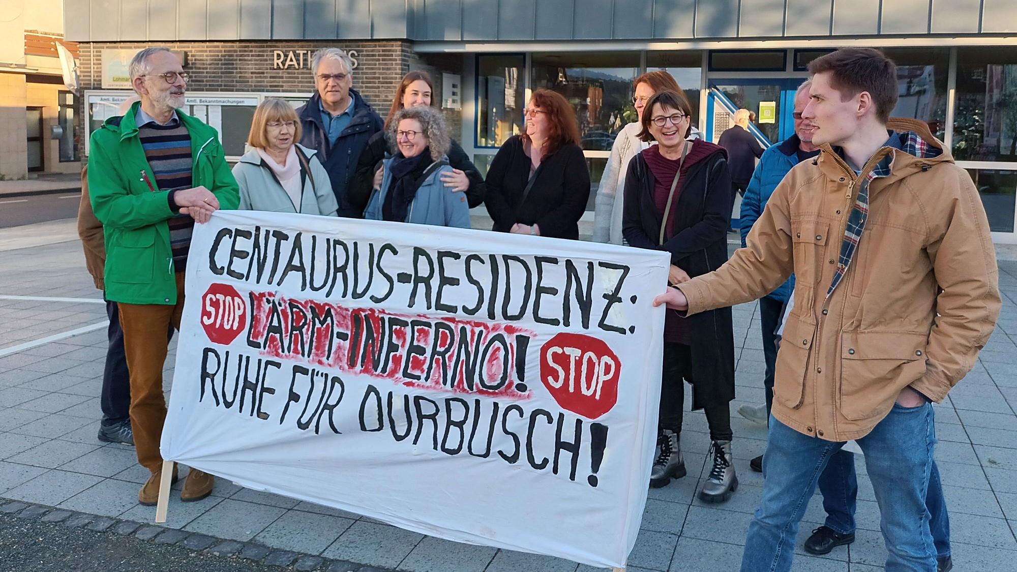 Einige Personen demonstrieren vor dem Rathaus. Sie halten ein Banner, auf dem steht: „Centaurus-Residenz: Lärm-Inferno! Ruhe für Durbusch!“