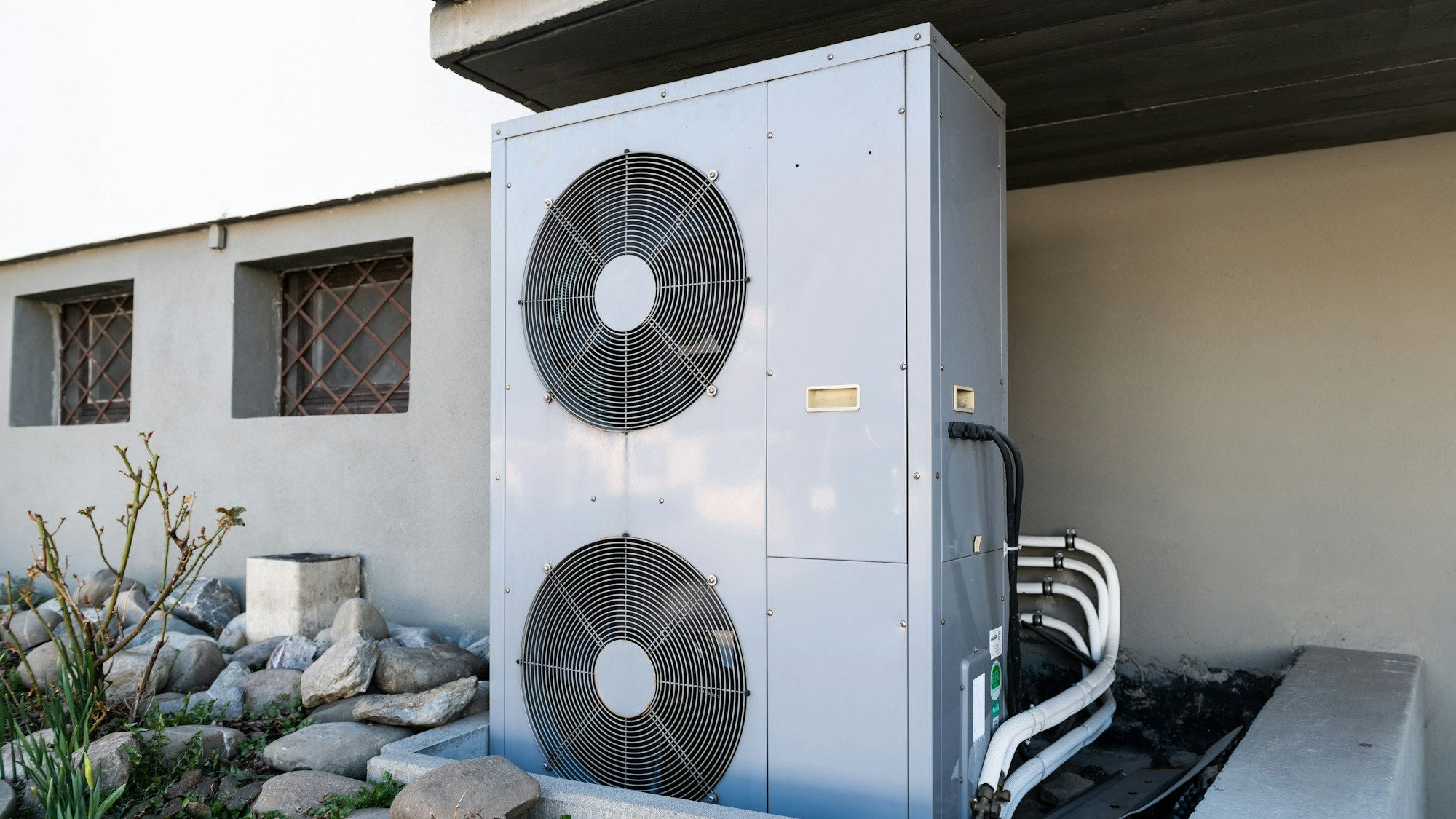 Die Lüftungsanlage einer Wärmepumpe steht vor einem Wohnhaus.