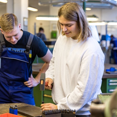 Ein Auszubildender zeigt einem Besucher ein Handwerk.