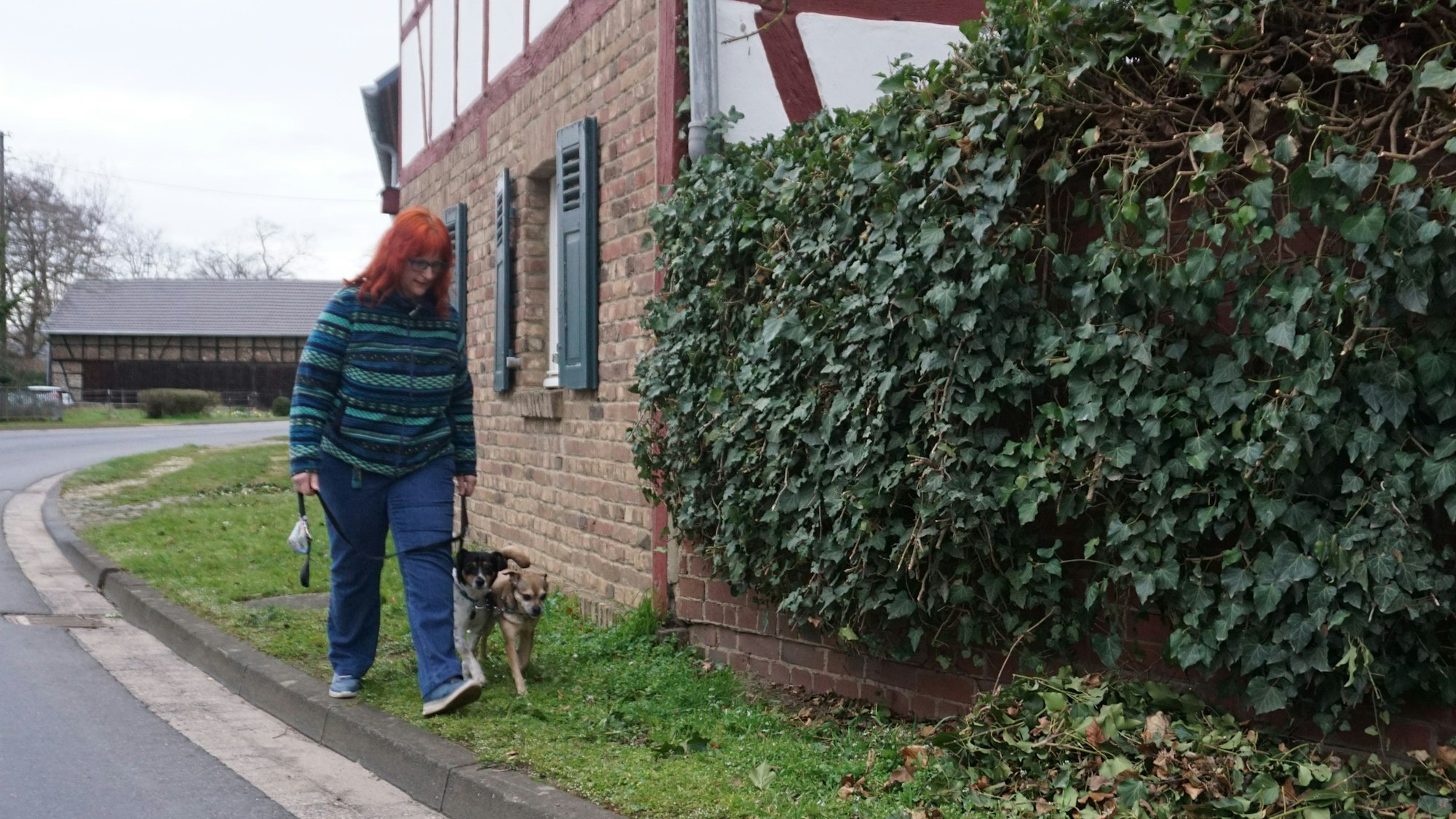 Der Bürgersteig, auf dem Angelika Gerhards-Wagner mit ihrem Hund unterwegs ist, ist schmal und mit Gras bewachsen.