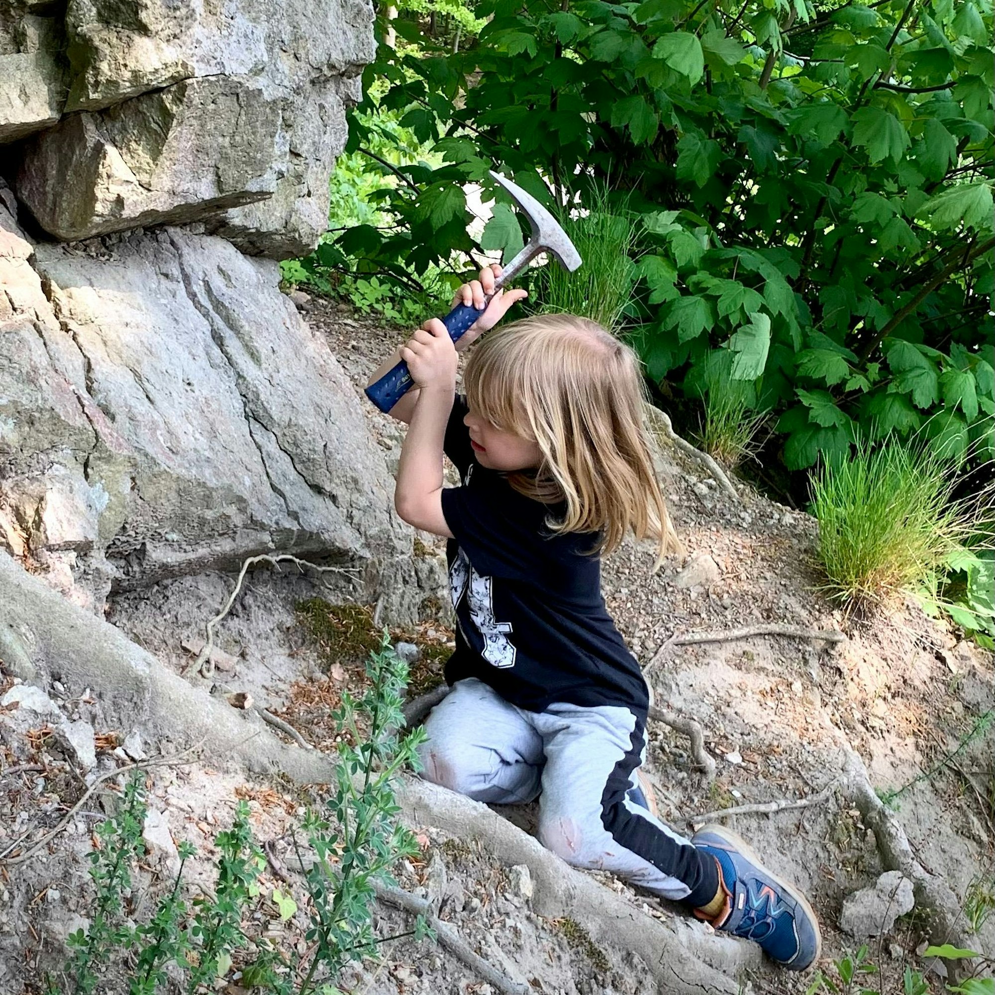 Ein Junge klopft mit einem Hammer Steine auf dem Oelberg.