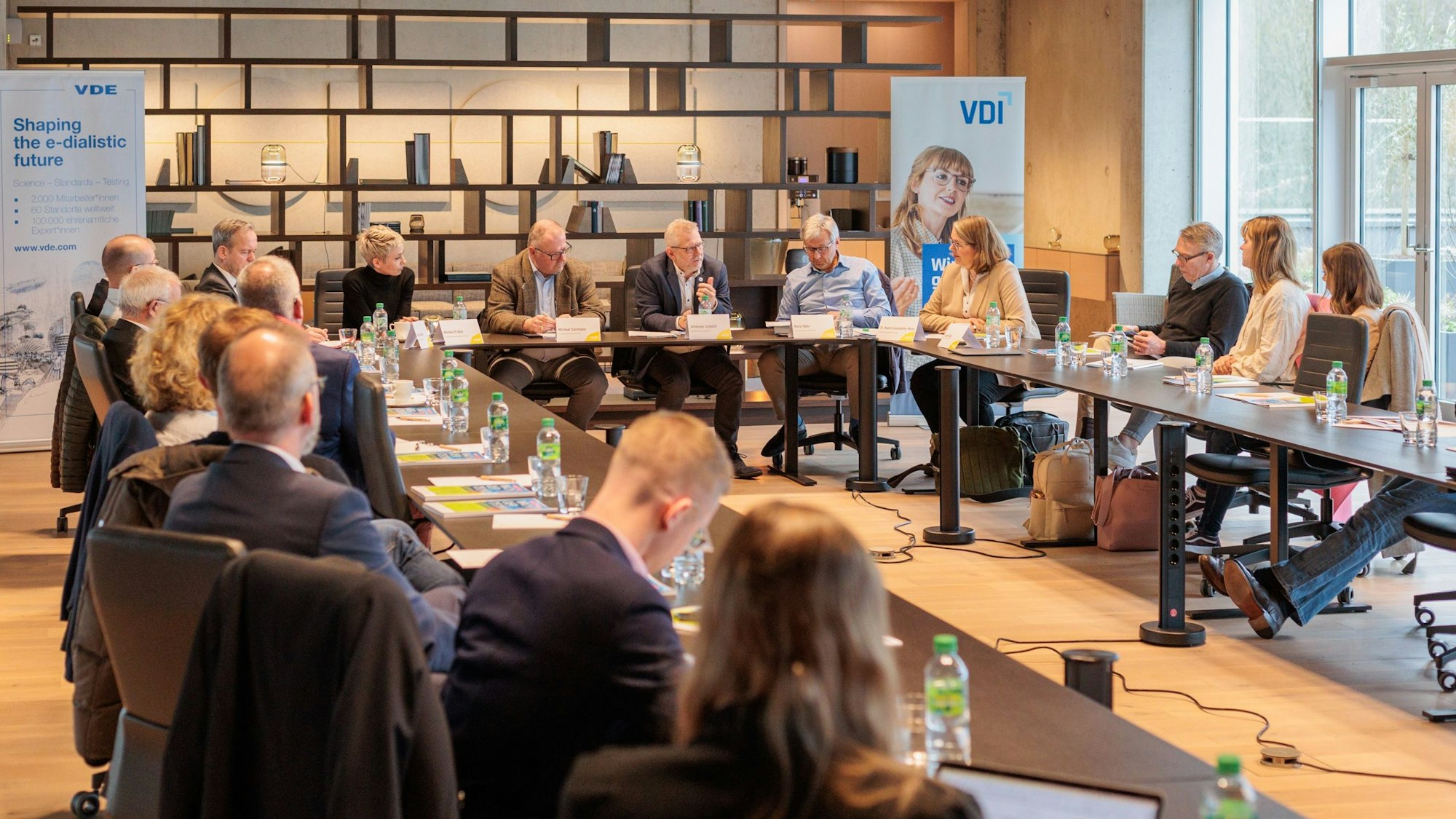 Mehrere Menschen sitzen an kreisförmig angeordneten Tischen zusammen.