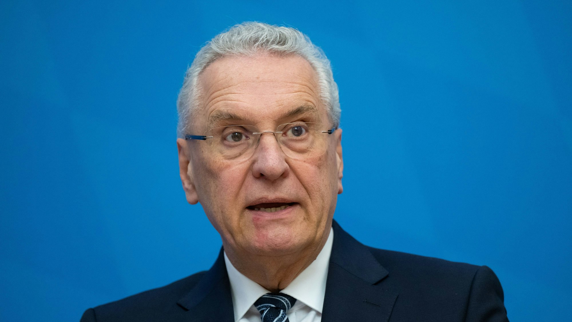 Joachim Herrmann steht vor einer blauen Wand.