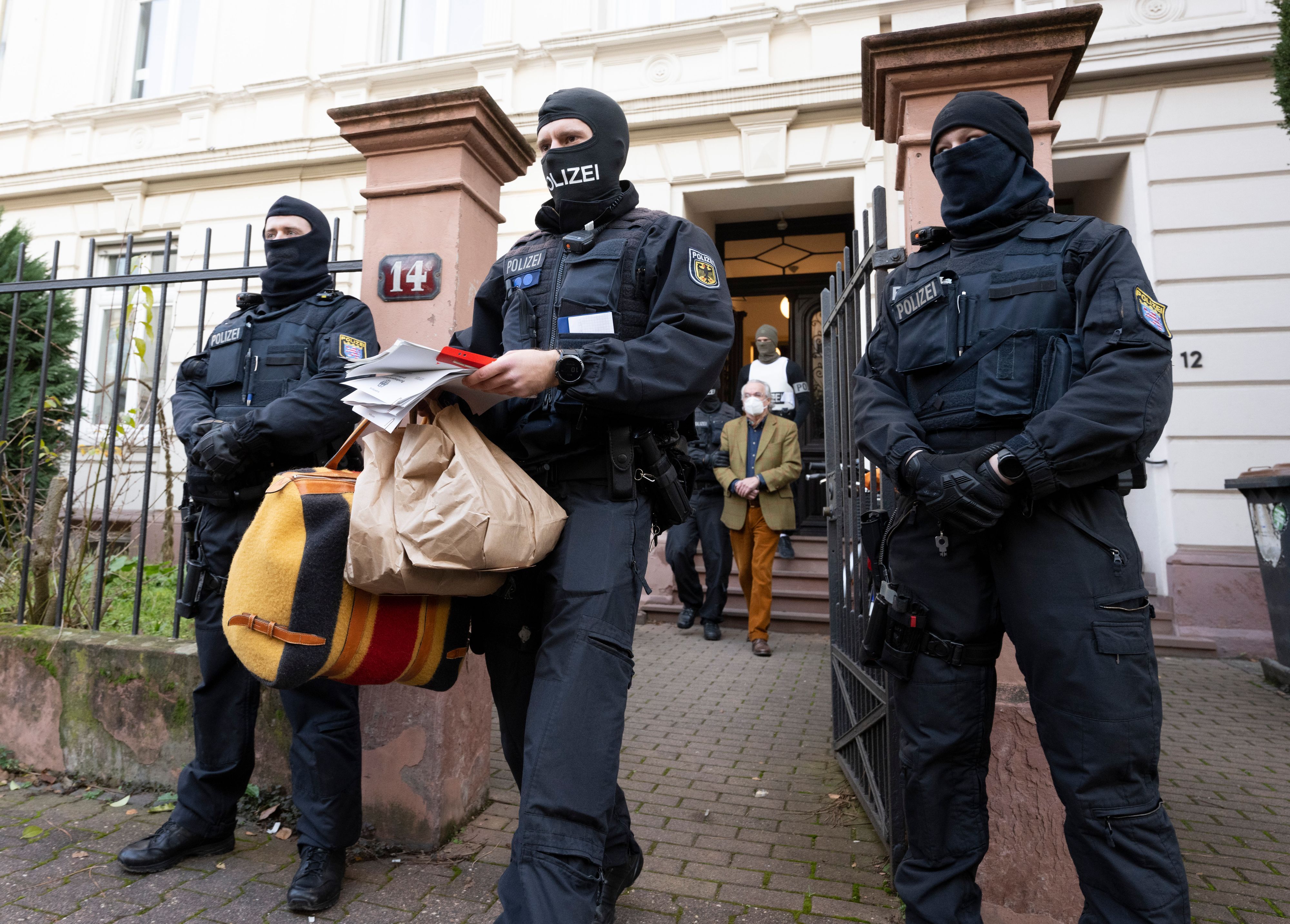 Bei einer Razzia gegen sogenannte «Reichsbürger» führen vermummte Polizisten, nach der Durchsuchung eines Hauses Heinrich XIII Prinz Reuß (hinten, Mitte) zu einem Polizeifahrzeug. Ein Polizist trägt dabei, Tüten, eine Tasche und Papiere.