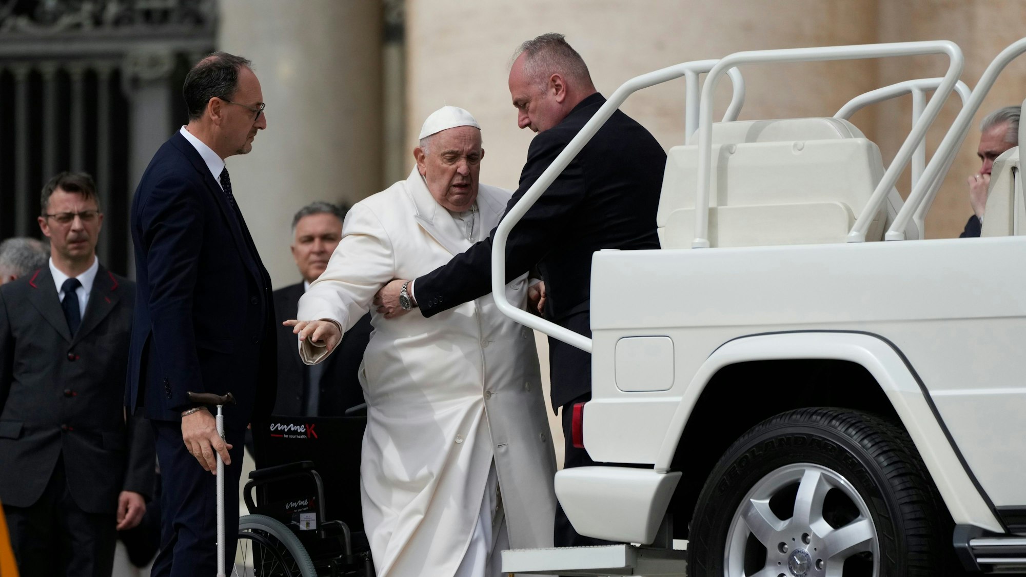 Papst Franziskus (2.v.r) wird am Ende der wöchentlichen Generalaudienz auf dem Petersplatz in sein Auto geholfen, während Massimiliano Strappetti (l), persönlicher medizinischer Betreuer des Papstes, seinen Stock hält.