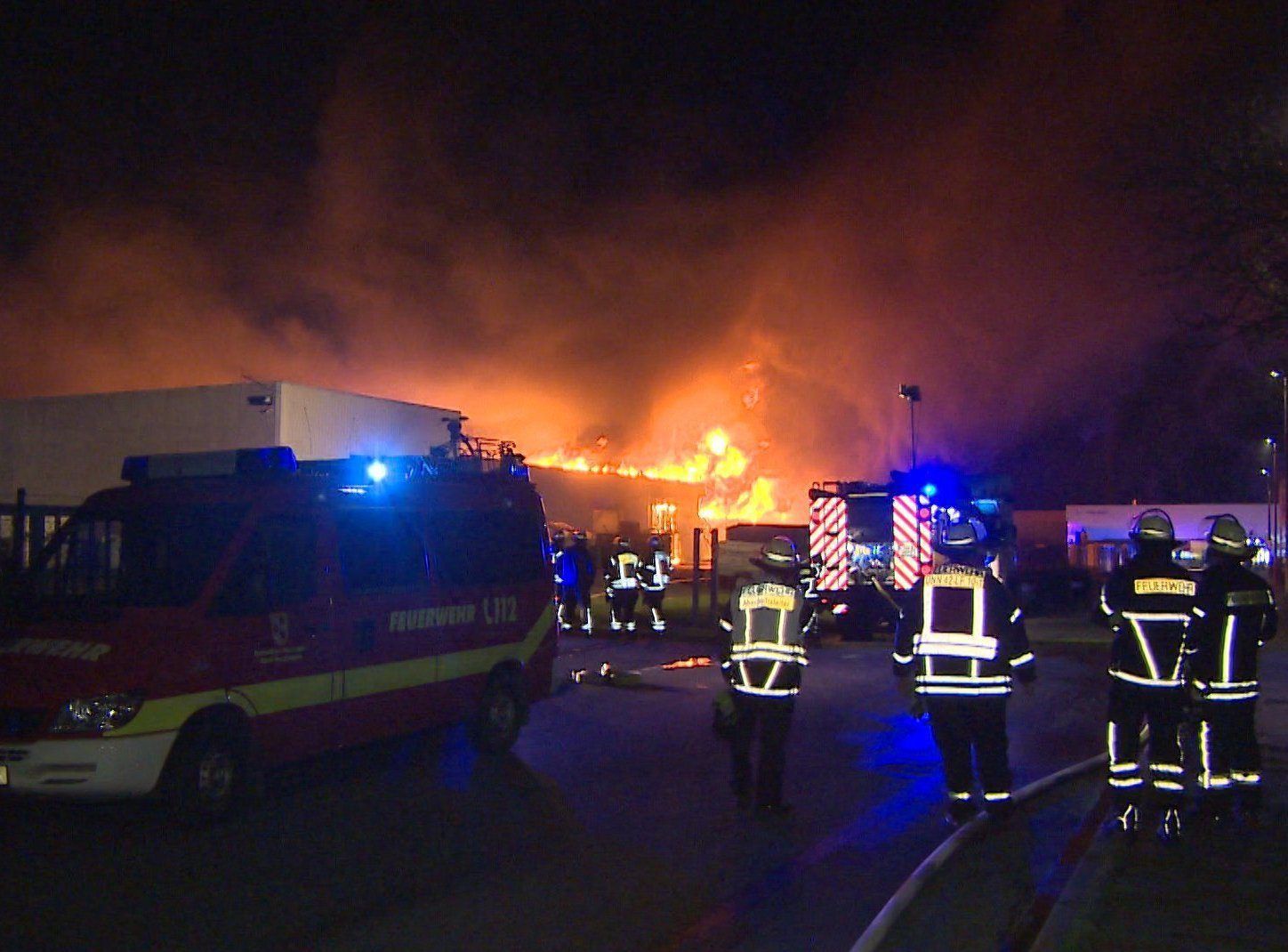 Unna: Einsatzkräfte der Feuerwehr stehen an einem brennenden Firmengebäude