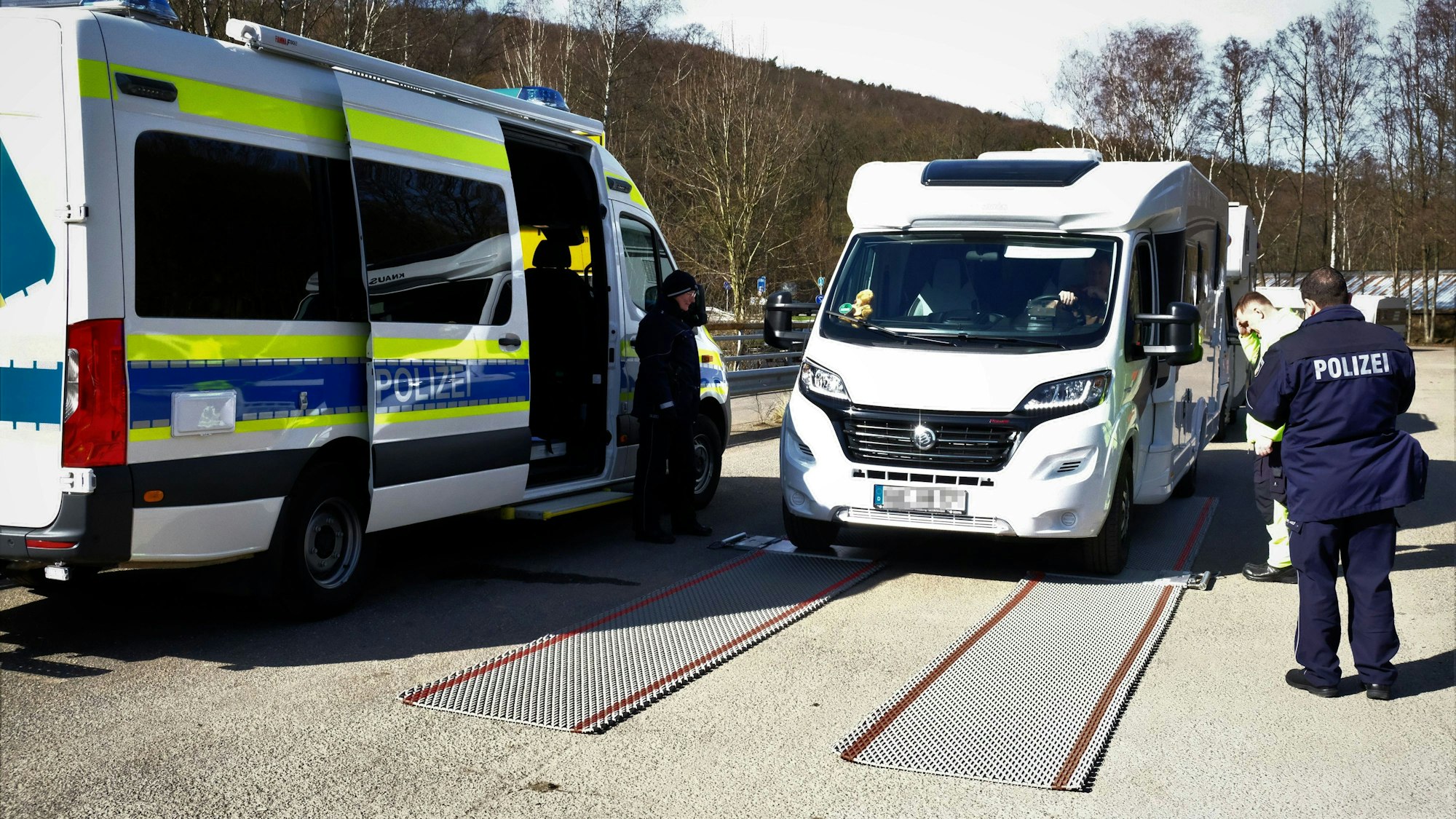 Ein Wohnmobil steht neben einem Polizeiwagen.
