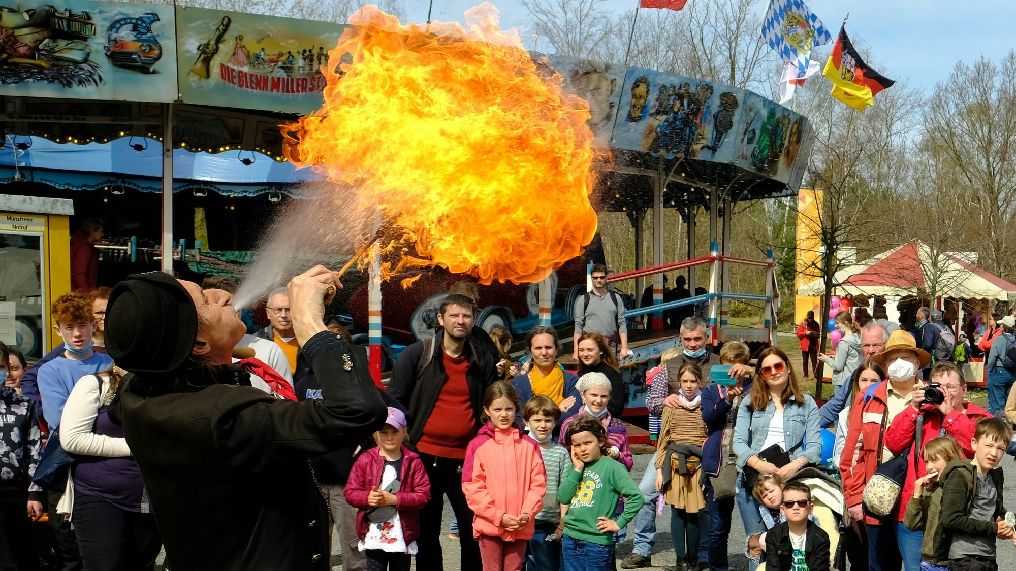 Ein Publikum schaut einem Feuerspucker zu.