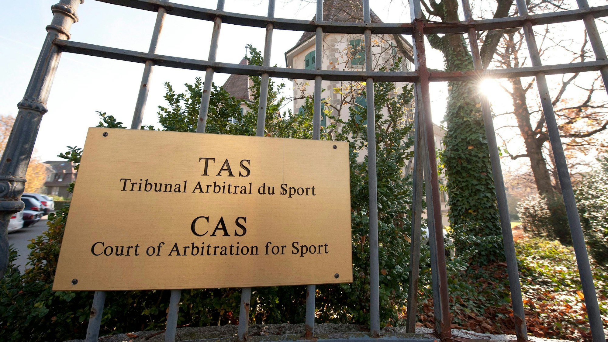 Außenansicht vom Internationalen Sportgerichtshof (CAS) in der schweizerischen Stadt Lausanne. Ein metallenes Schild hängt an einem Eisenzaun.