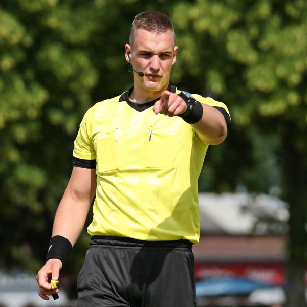 Tobias Esch beim Pfeifen eines Fußballspiels. Mit dem Finger zeigt er nach vorne.