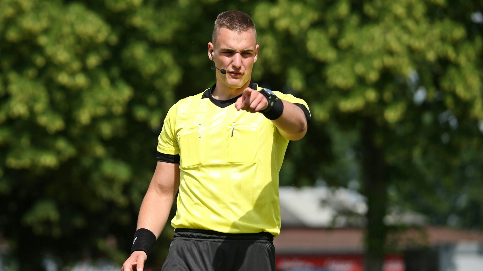 Tobias Esch beim Pfeifen eines Fußballspiels. Mit dem Finger zeigt er nach vorne.