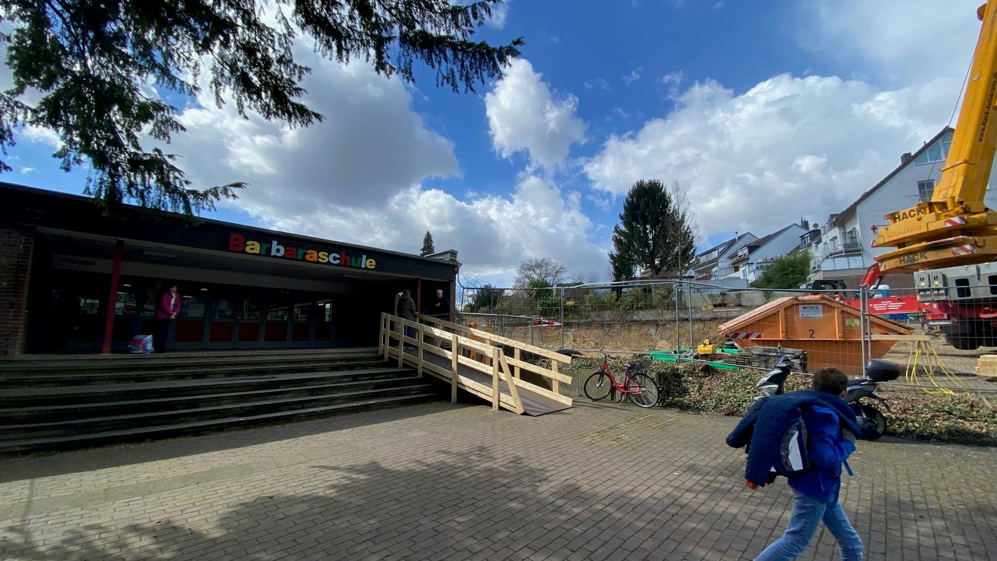 Blick auf den Eingang der Schule. Rechts davon ist die Baustelle zu sehen.
