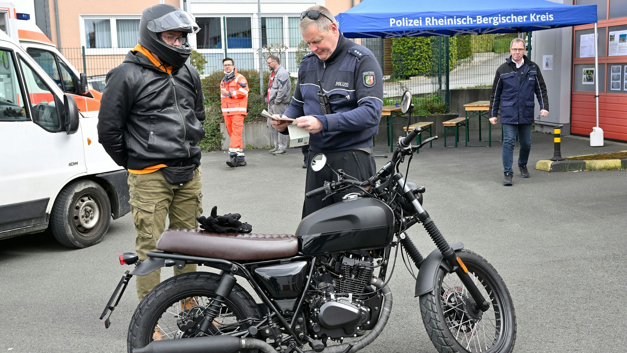 Die Polizei kontrolliert einen Zweiradfahrer.