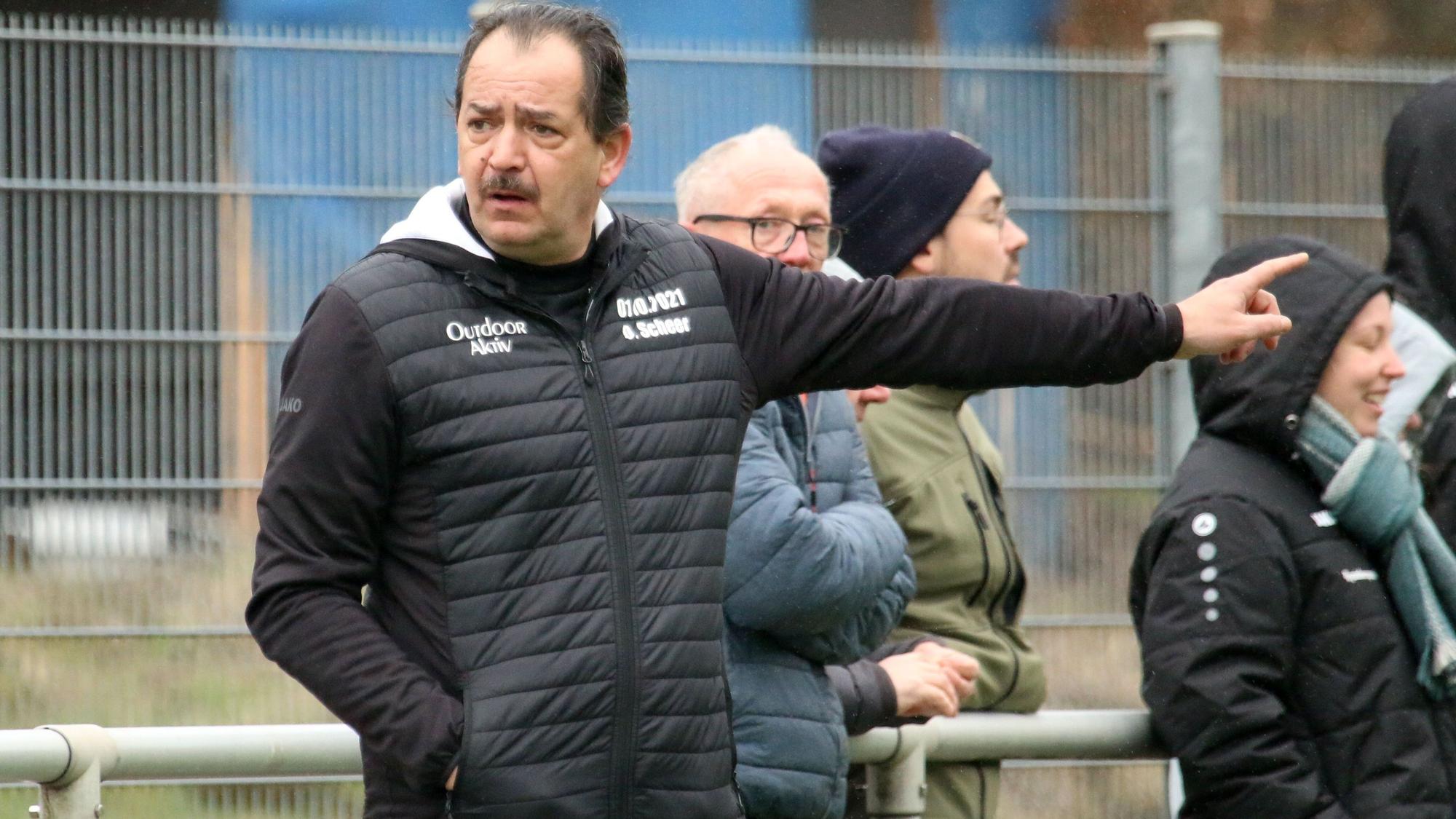 Das Bild zeigt Dirk Scheer an der Seitenlinie, wie er aufs Spielfeld zeigt.