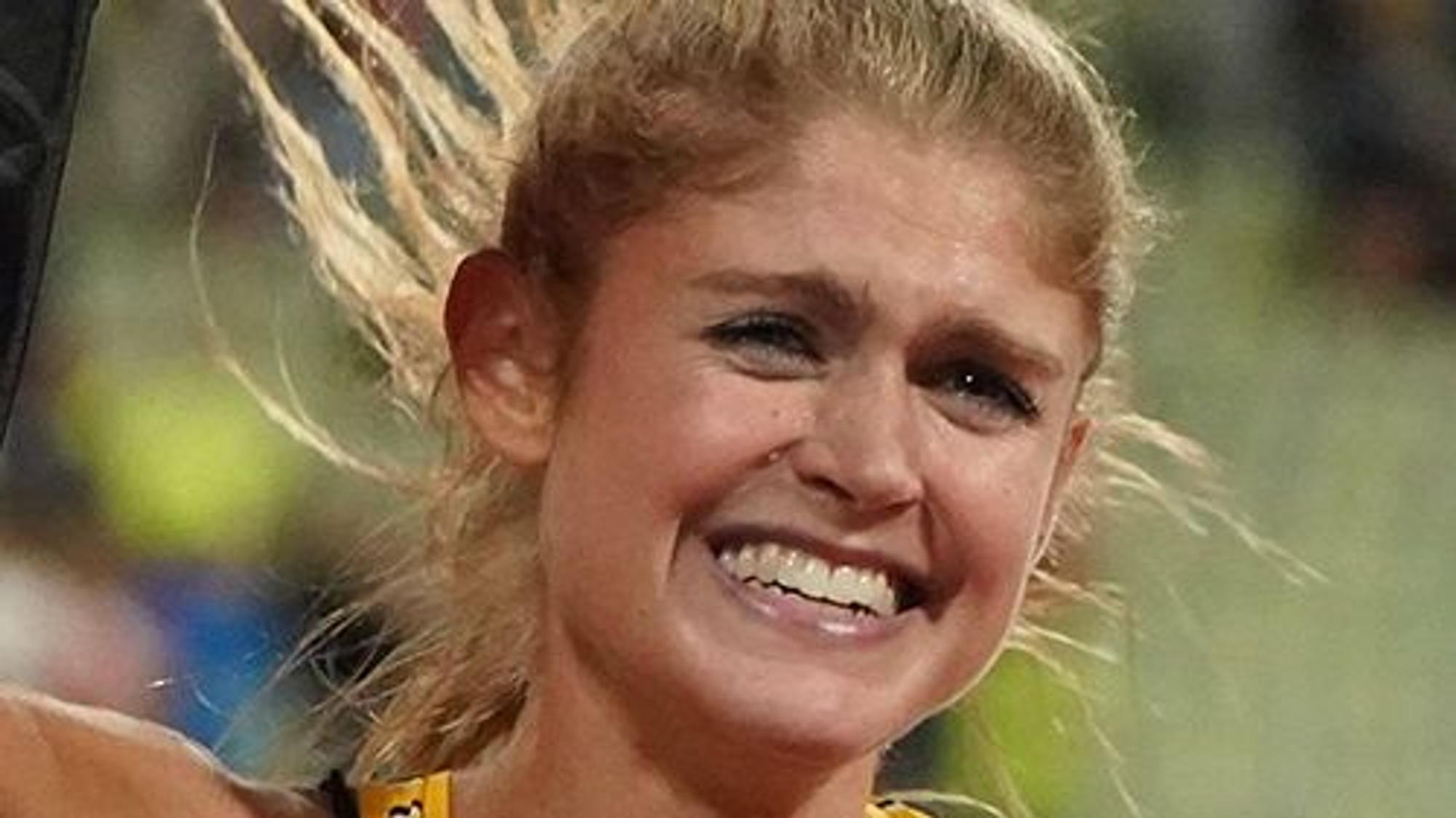 Die Leichtathletin lacht nach einem beendeten Lauf in die Kamera.