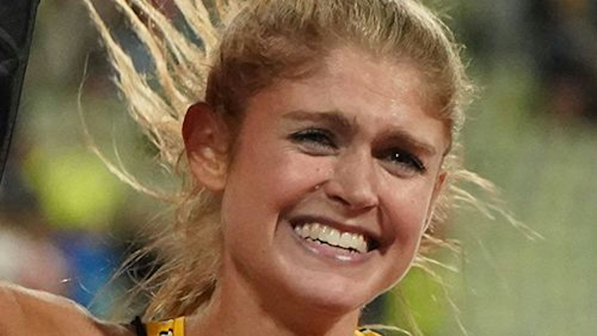 Die Leichtathletin lacht nach einem beendeten Lauf in die Kamera.