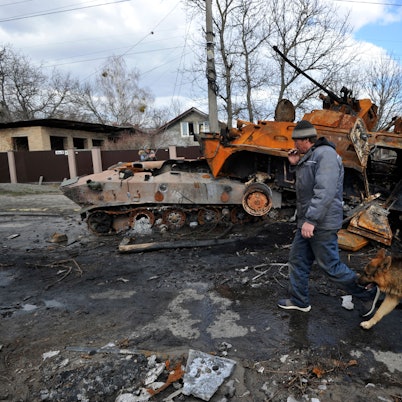 Ein Mann geht mit seinem Hund an zerstörten Militärfahrzeugen der russischen Armee vorbei. Angesichts der schockierenden Gräueltaten in der ukrainischen Stadt Butscha bereitet der Westen schärfere Sanktionen gegen Russland vor. +++ dpa-Bildfunk +++