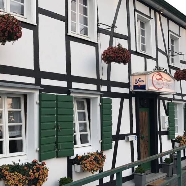 Die Fassade der Cramer Stuben in Odenthal, ein Fachwerkhaus mit grünen Fensterläden.