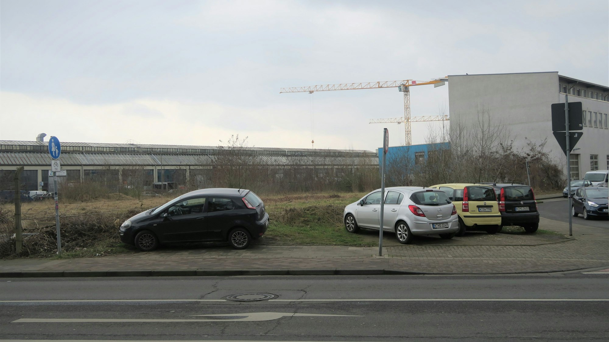 Eine Brachlandschaft liegt an einer Straße.