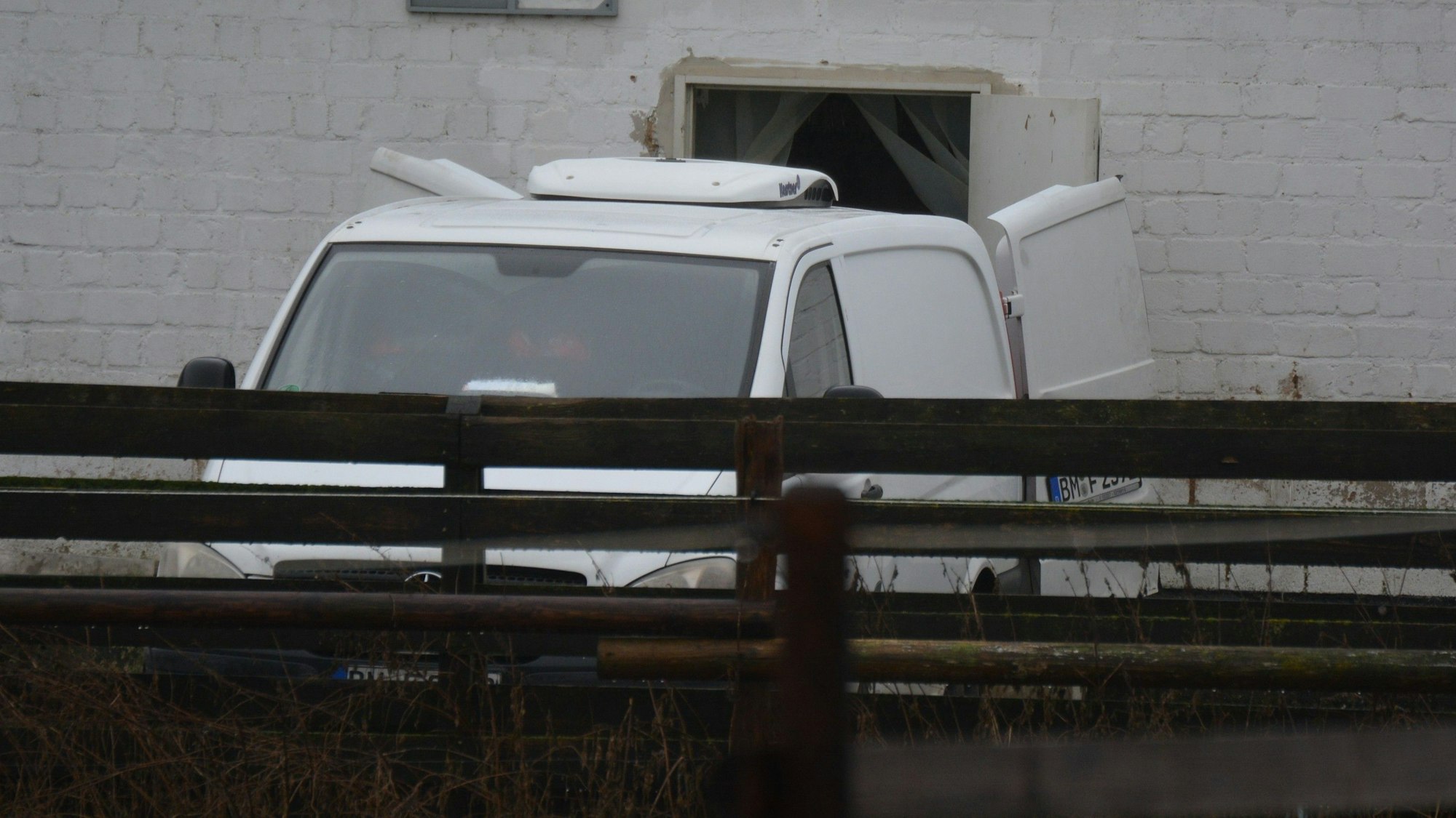 Das Bild zeigt einen weißen Kühlwagen mit offenen Türen, vor einem stillgelegten Schlachtbetrieb.