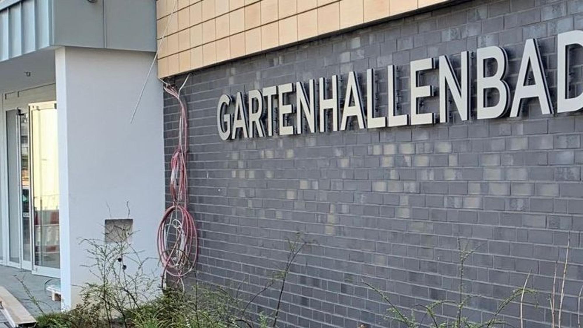 Das Bild zeigt das Gebäude des Schwimmbads von der Außenseite mit dem Schriftzug Gartenhallenbad.