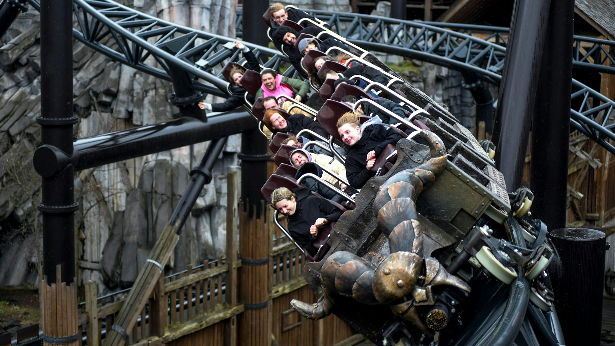 Das Bild zeigt eine mit Personen besetzte Achterbahn während der Fahrt.