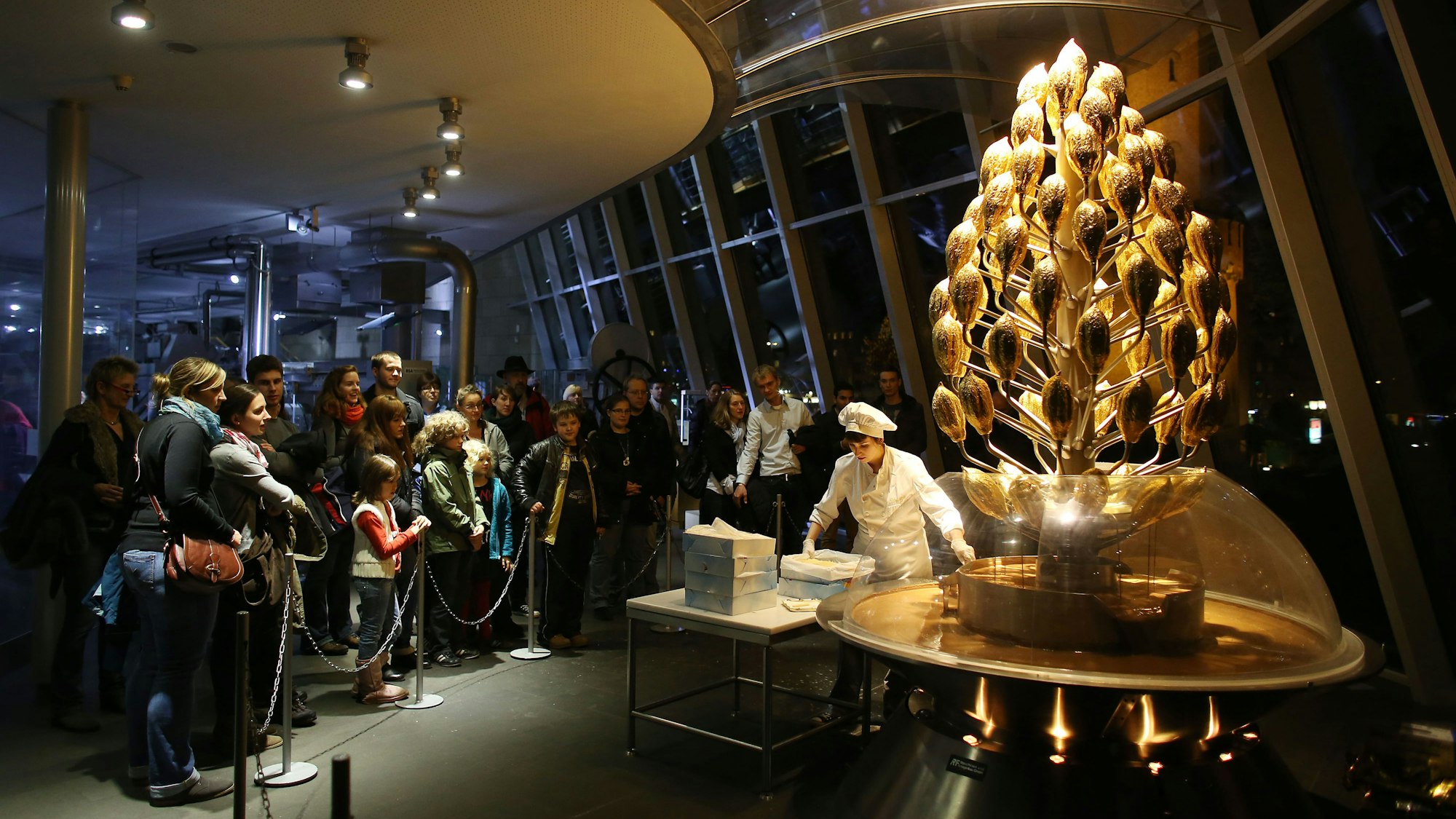 Museumsbesucher stehen im Schokoladen-Museum am Schokoladenbrunnen an.