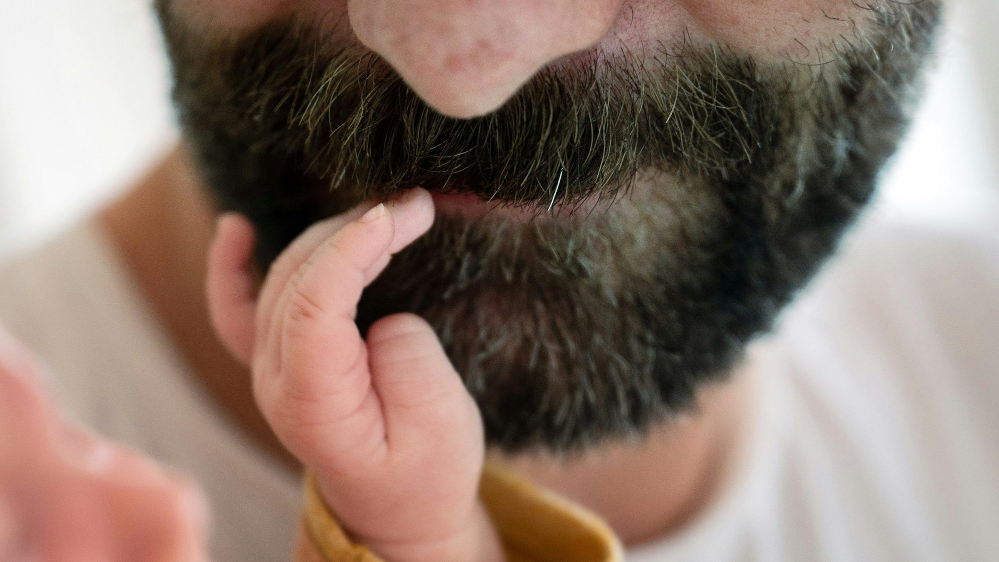 Ein Kind fasst seinem Vater in den Bart.