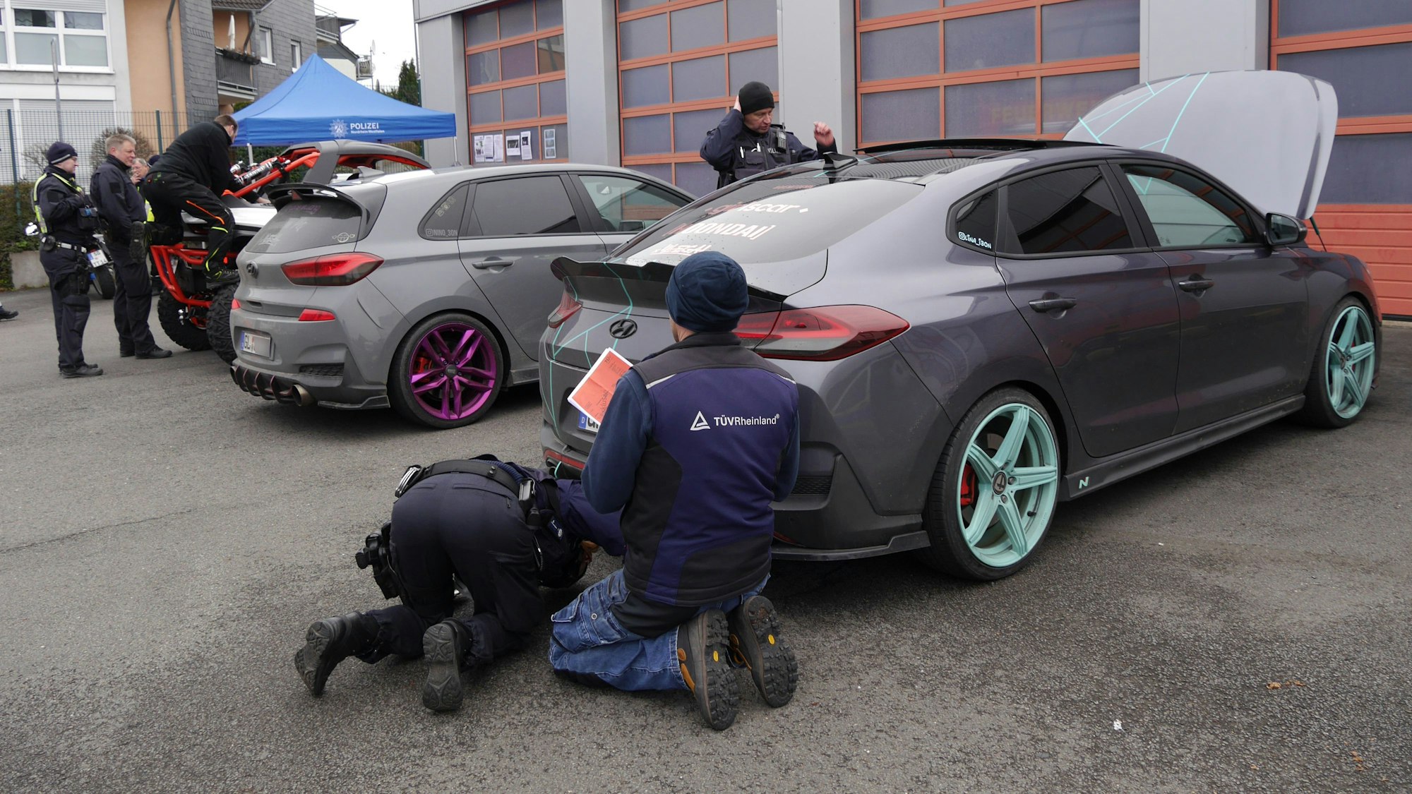 ein Polizeibeamter und ein Tüv-Prüfer untersuchen einen Sportwagen.