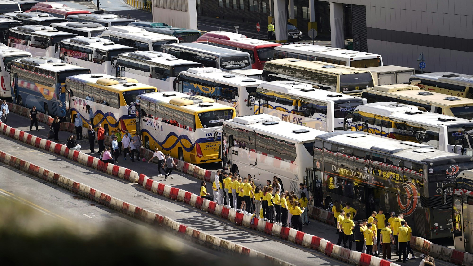 Menschen stehen und warten vor ihren Reisebussen auf die Einfahrt in den Hafen von Dover.