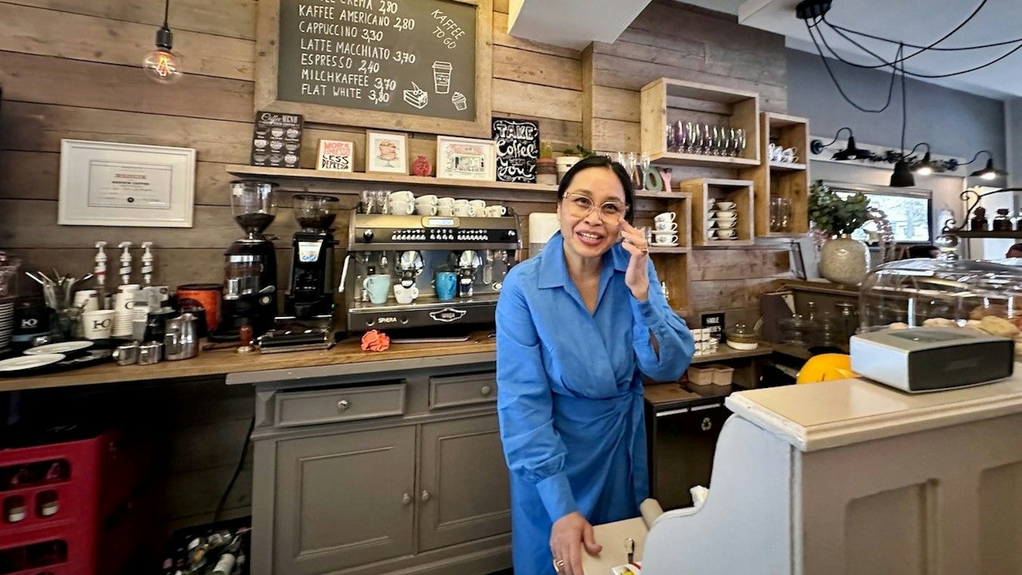 Die Besitzerin des Cafés steht hinter ihrem Tresen.