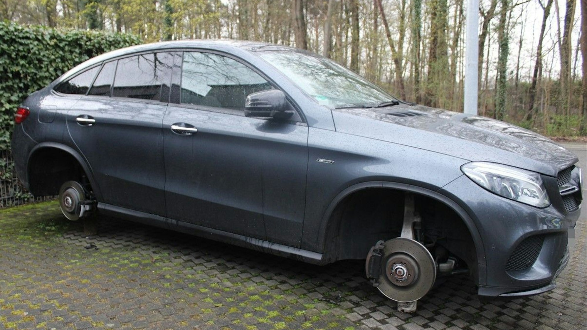 Ein schwarzer Mercedes steht ohne Reifen auf einem Parkplatz.