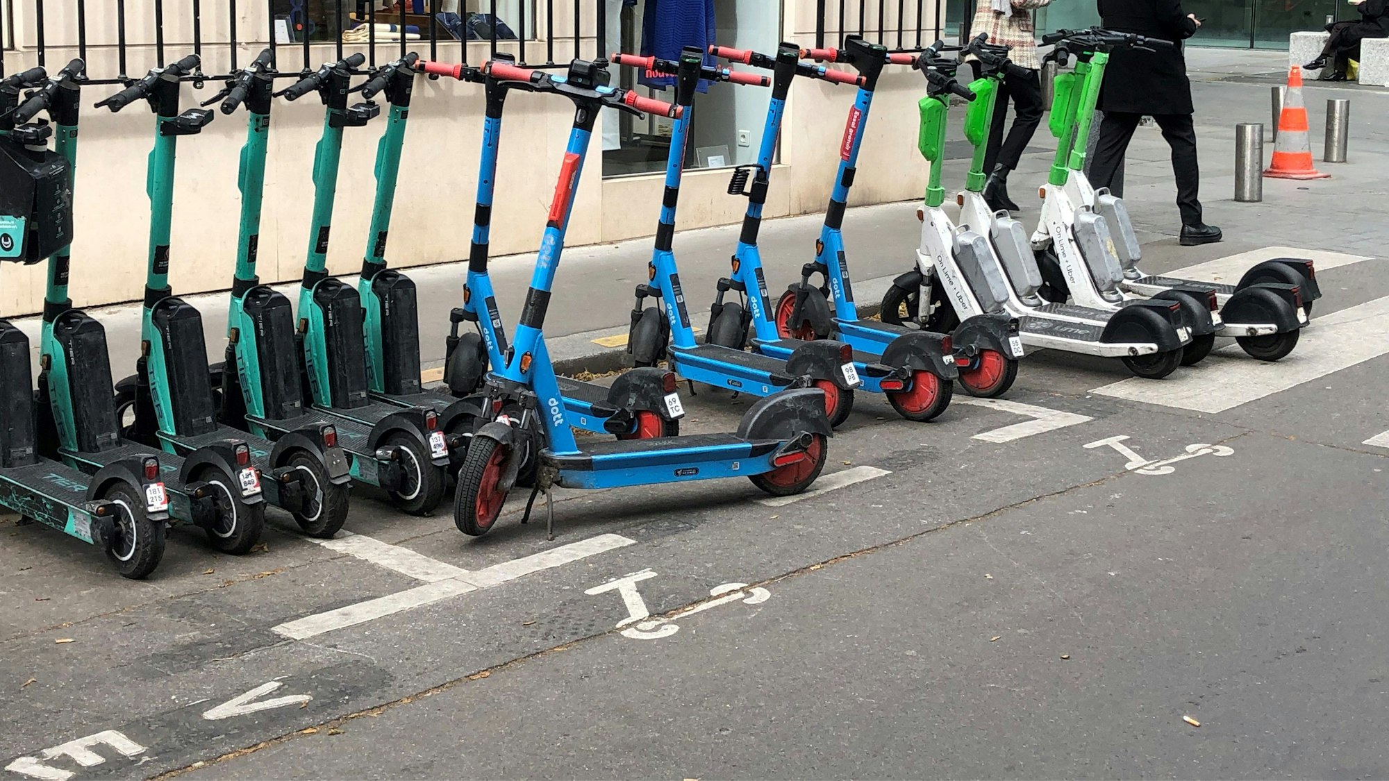 E-Scooter von drei verschiedenen Anbietern stehen auf einem dafür vorgesehenen Parkplatz. (Symbolbild)