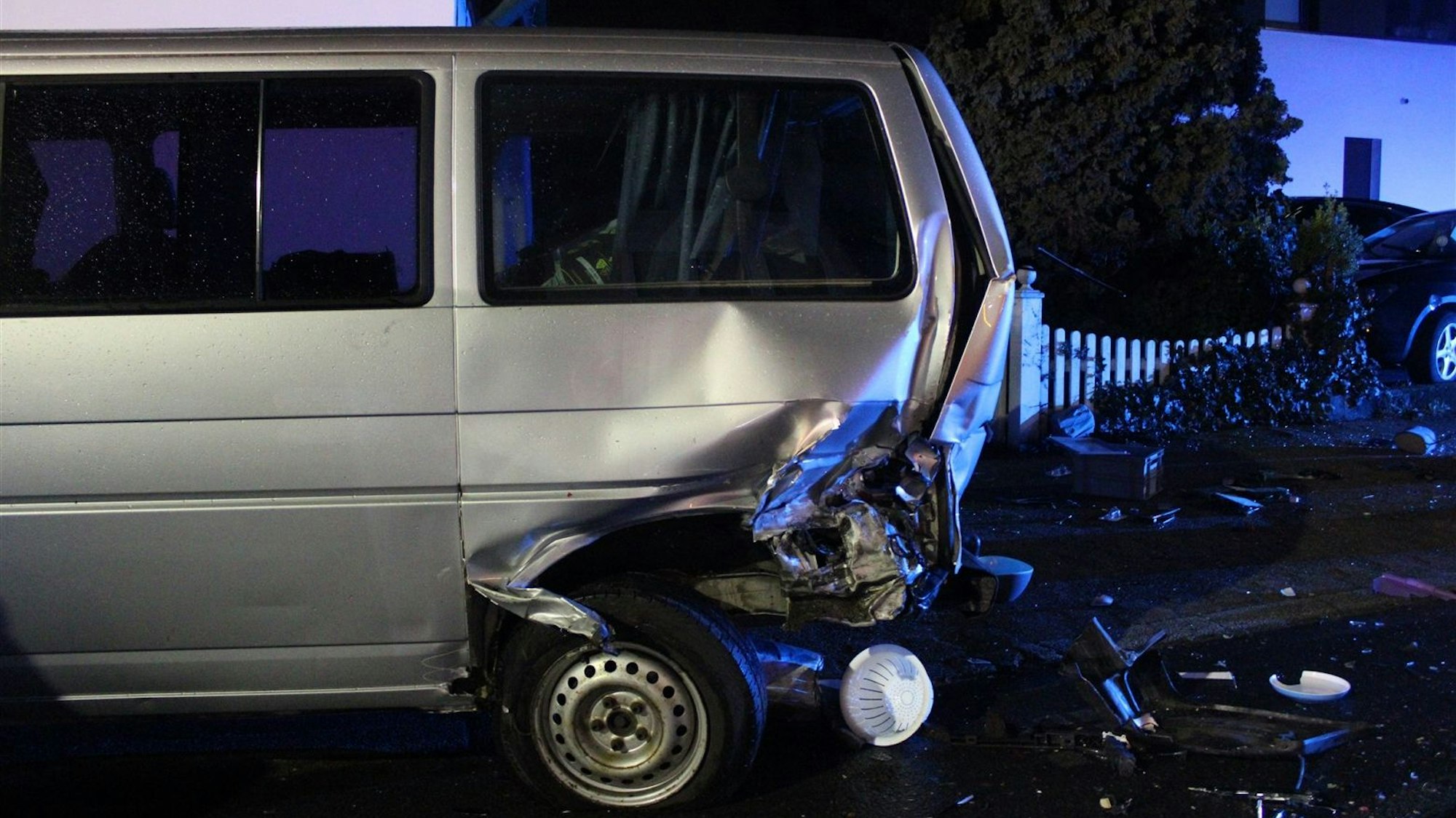 Ein beschädigter silberner Van steht am Unfallort.