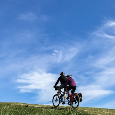 Ein Paar fährt mit einem Tandem einen Hügel hinauf.