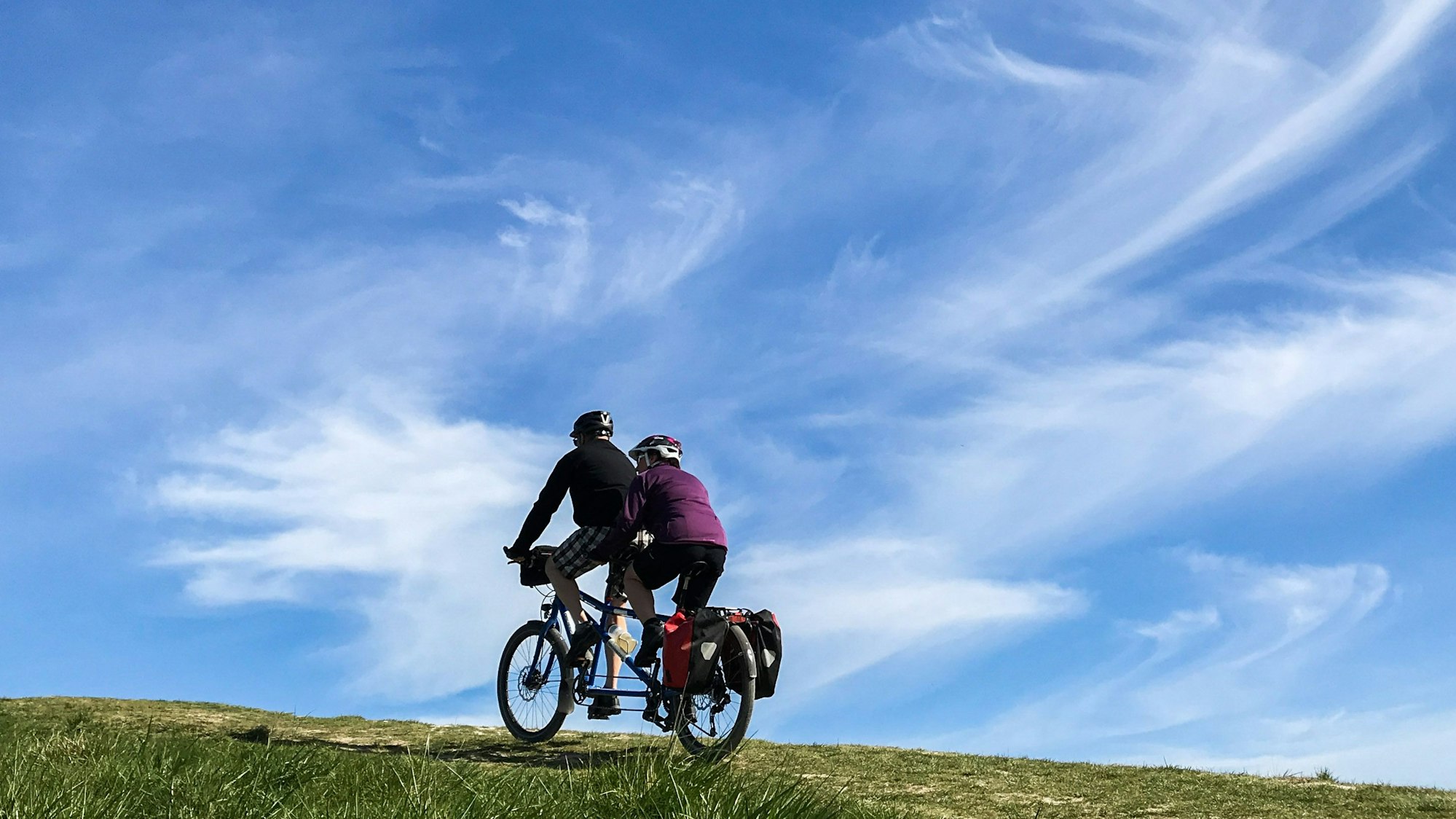 Ein Paar fährt mit einem Tandem einen Hügel hinauf.