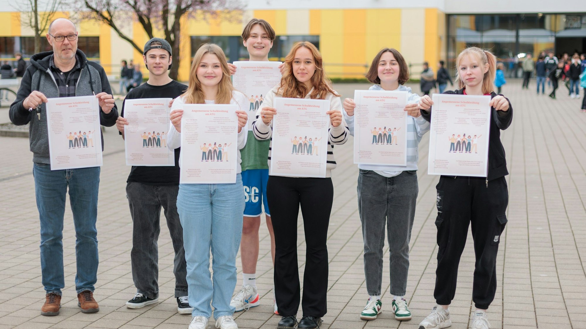 Zu sehen sind Menschen, die jeweils ein Plakat vor sich halten.