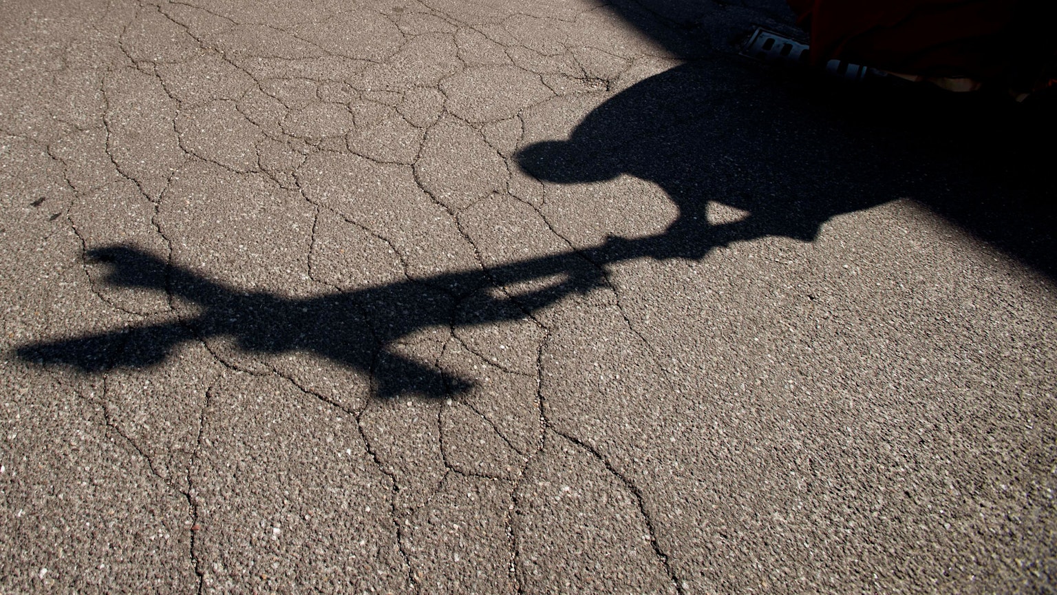 Der Schatten eines Priesters, der am Karfreitag bei einer Zeremonie ein Kreuz trägt, fällt auf das Pflaster.