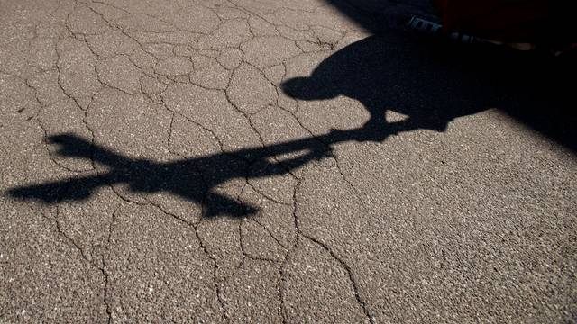 Der Schatten eines Priesters, der am Karfreitag bei einer Zeremonie ein Kreuz trägt, fällt auf das Pflaster.