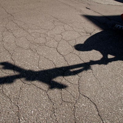 Der Schatten eines Priesters, der am Karfreitag bei einer Zeremonie ein Kreuz trägt, fällt auf das Pflaster.