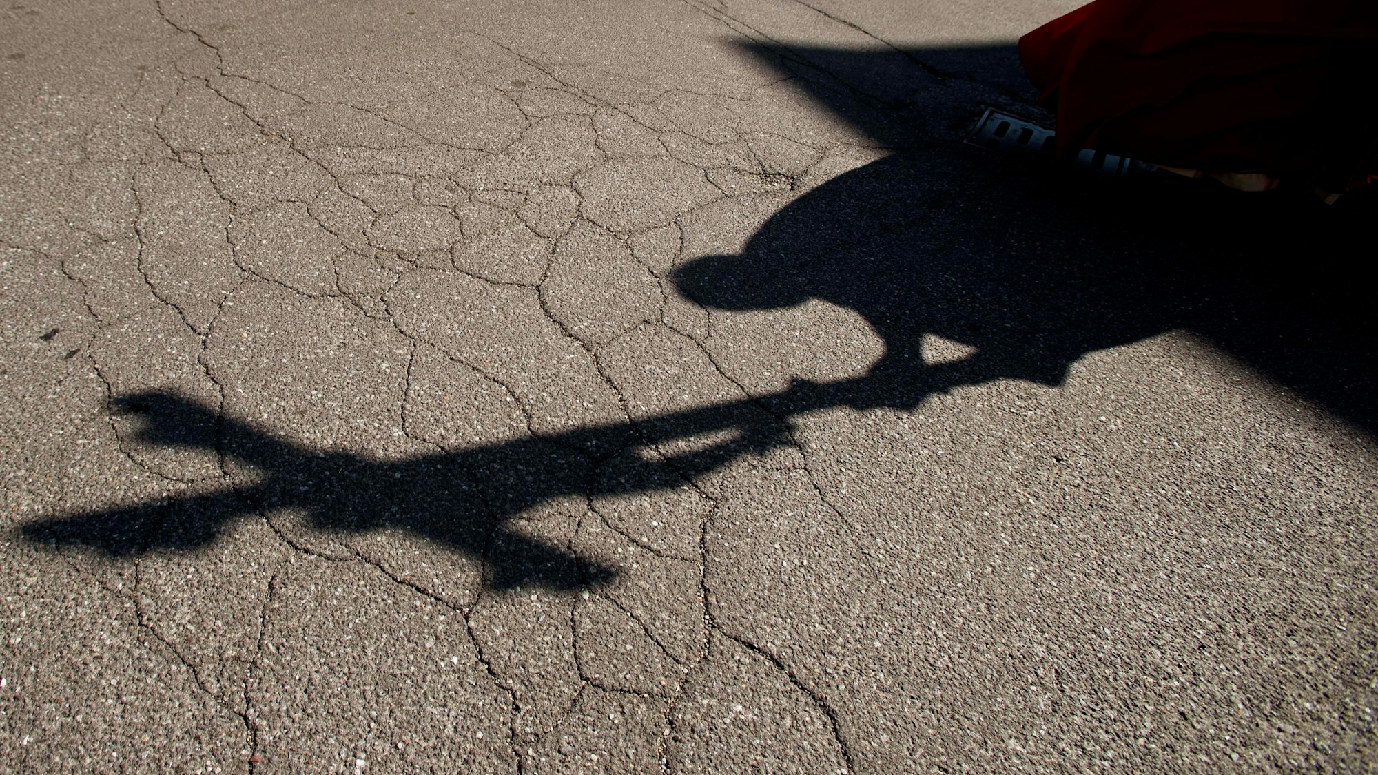 Der Schatten eines Priesters, der am Karfreitag bei einer Zeremonie ein Kreuz trägt, fällt auf das Pflaster.
