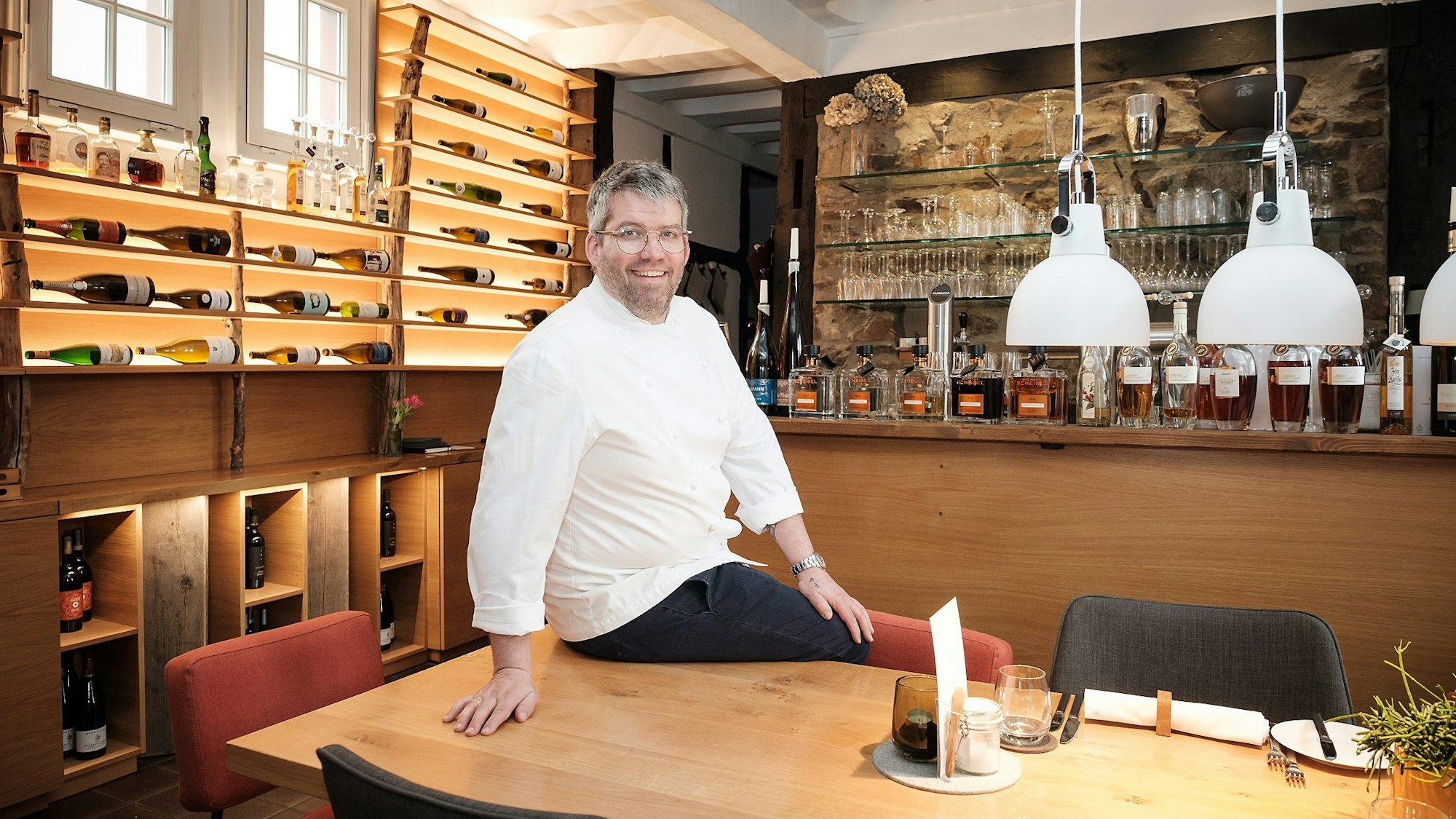 Lokal „Anna Seibert“ in Rheinbach von Benedikt Frechen. Der Inhaber sitzt auf einem Tisch in seinem Lokal.