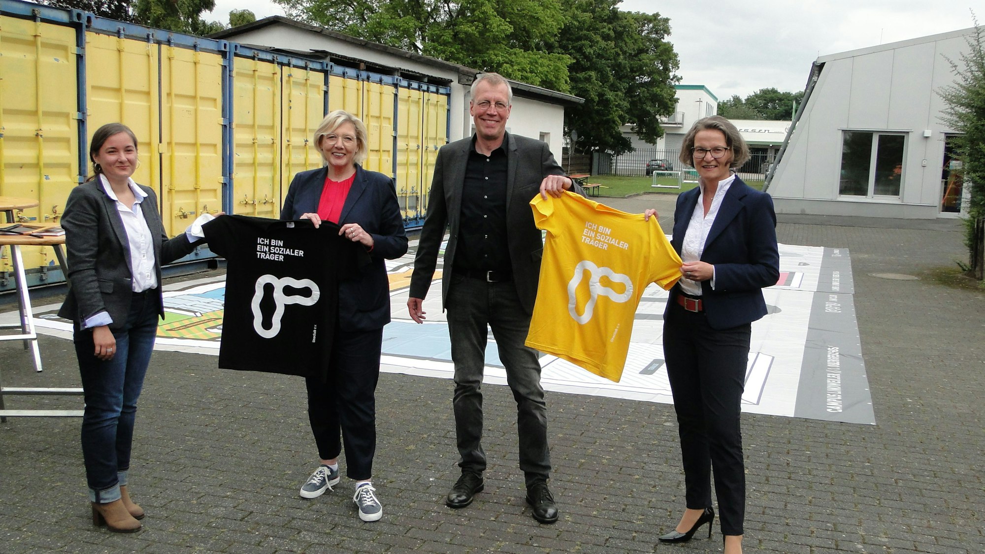 Drei Frauen und ein Mann halten T-Shirts in die Luft.