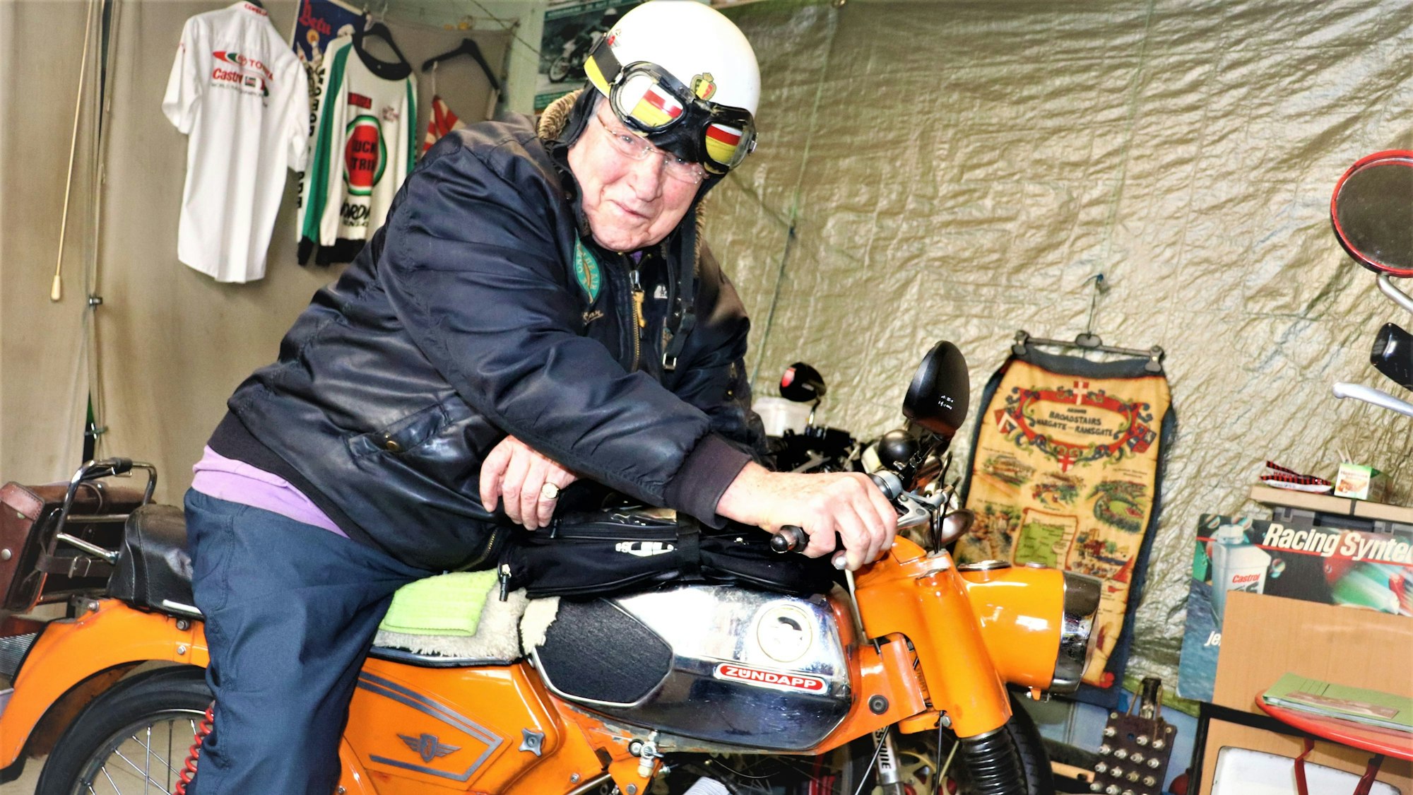 Der ehemalige Rennfahrer sitzt in seiner Garage auf seinem Motorrad.