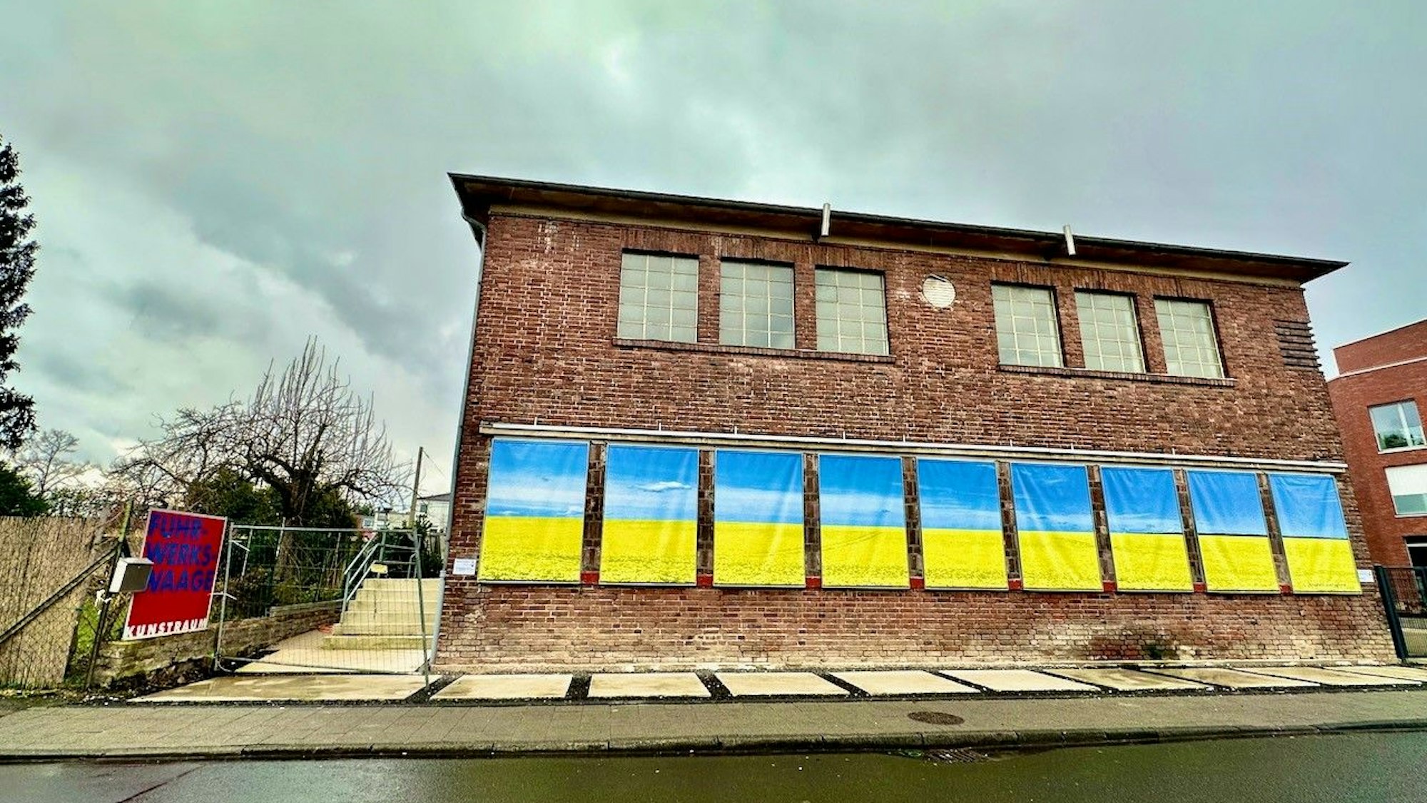 An einem Backsteinhaus hängen ukrainische Flaggen.