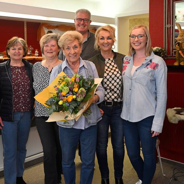Ingrid Wilms steht mit ihren Mitarbeiterinnen und ihrer Familie im Laden. Sie hält einen Blumenstrauß in den Händen.