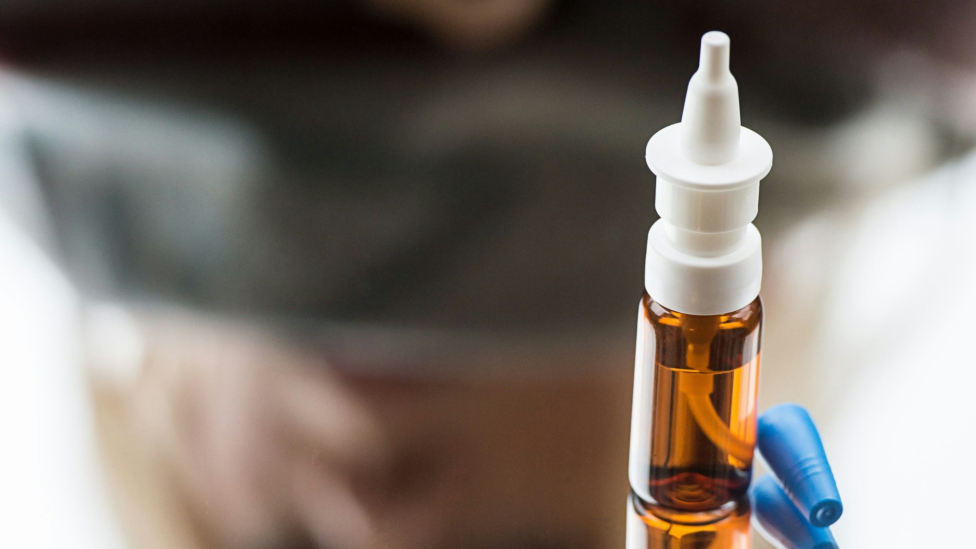 ILLUSTRATION - Eine Frau sieht auf eine Flasche Nasenspray, das auf einem Spiegel steht.